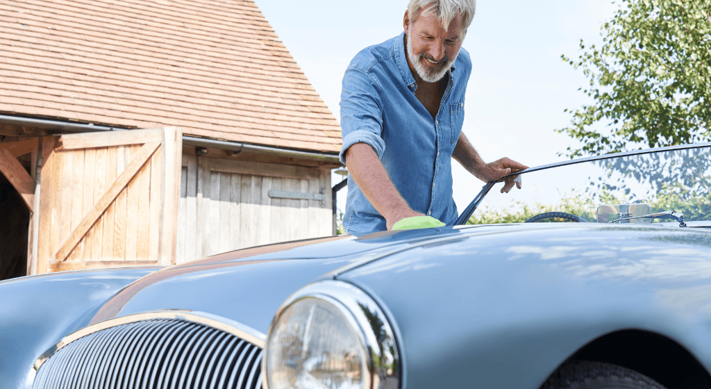 An older man cleaning his classic car